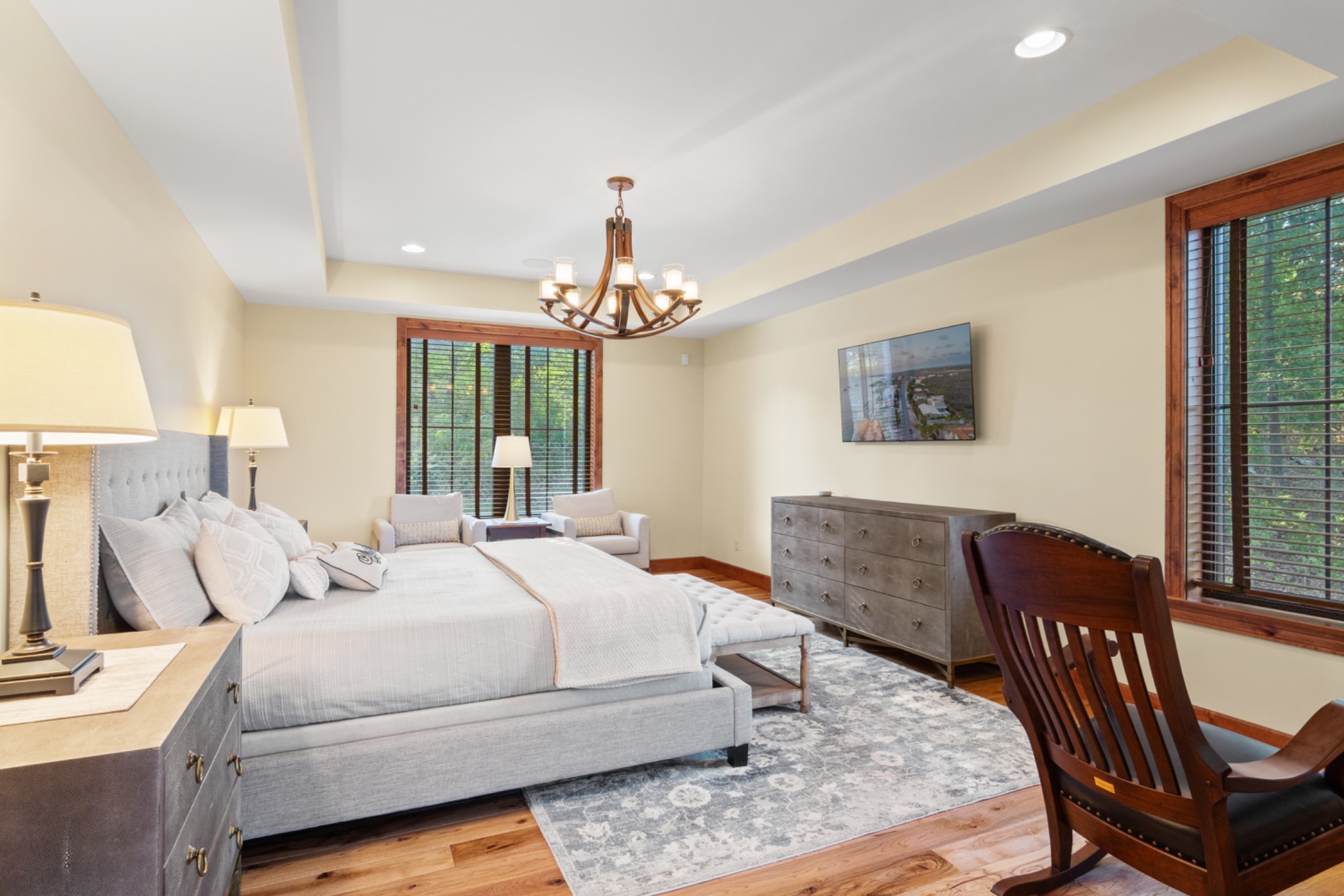 Bright bedroom with a large bed, seating area and wood-framed windows